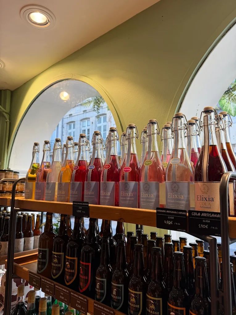 Des limonades artisanales Elixia en bouteilles à bouchon mécanique, devant les fenêtres en arche