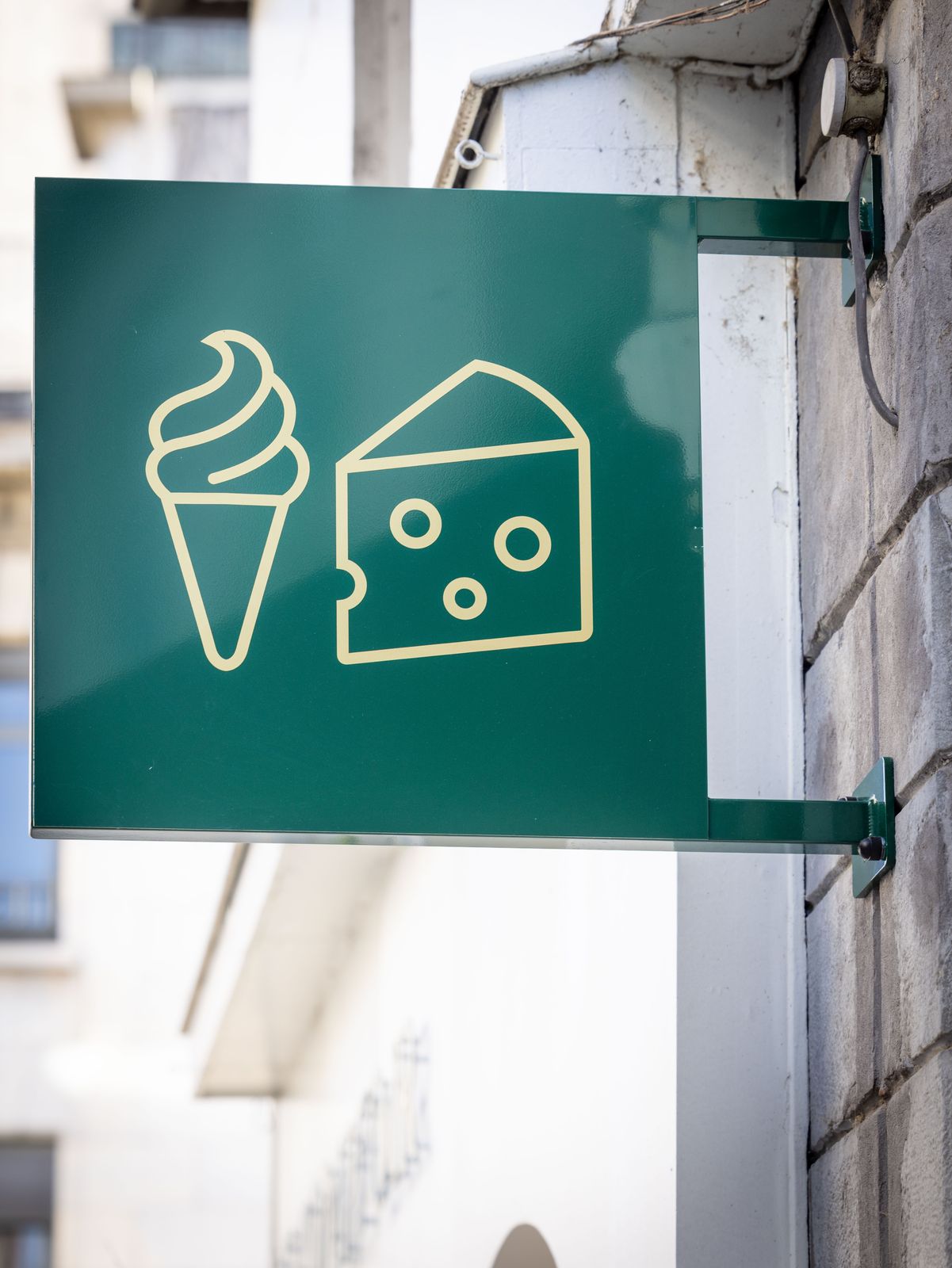 L'enseigne drapeau verte du Comptoir, avec une glace et un fromage dessinés au trait