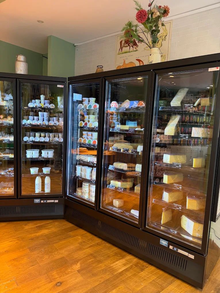 Les frigos de la boutique remplis de fromages, de crèmes et de beurres